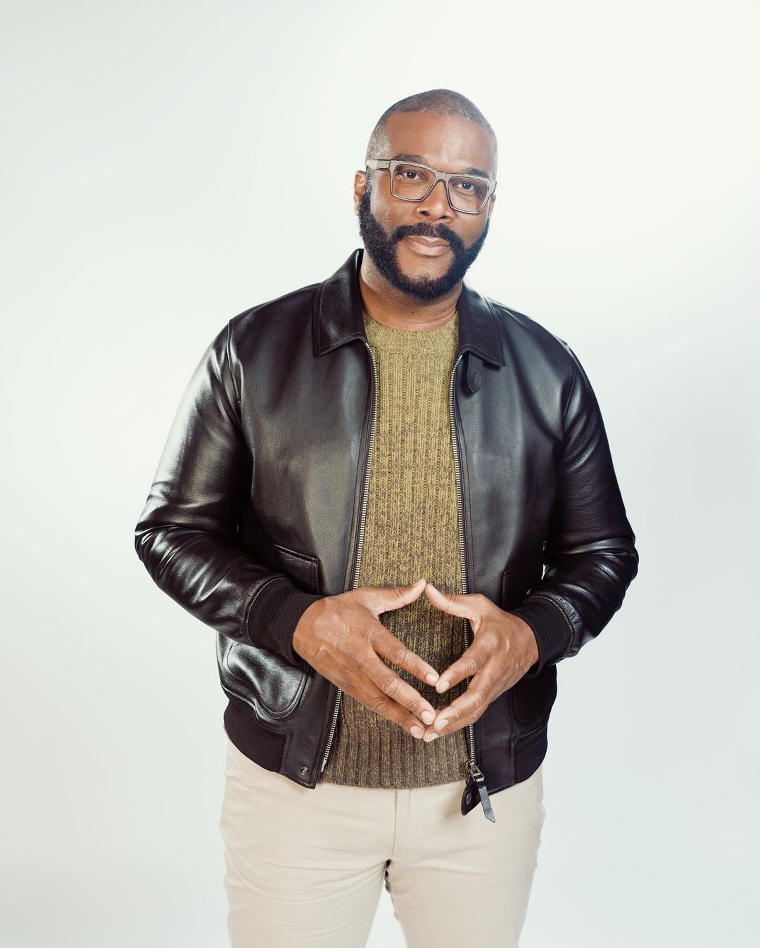 Portrait of Tyler Perry wearing a black leather jacket and glasses against a white background by photographer Braylen Dion