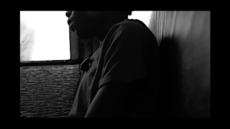 Monochrome close-up portrait of a young person seated indoors near a window by Braylen Dion