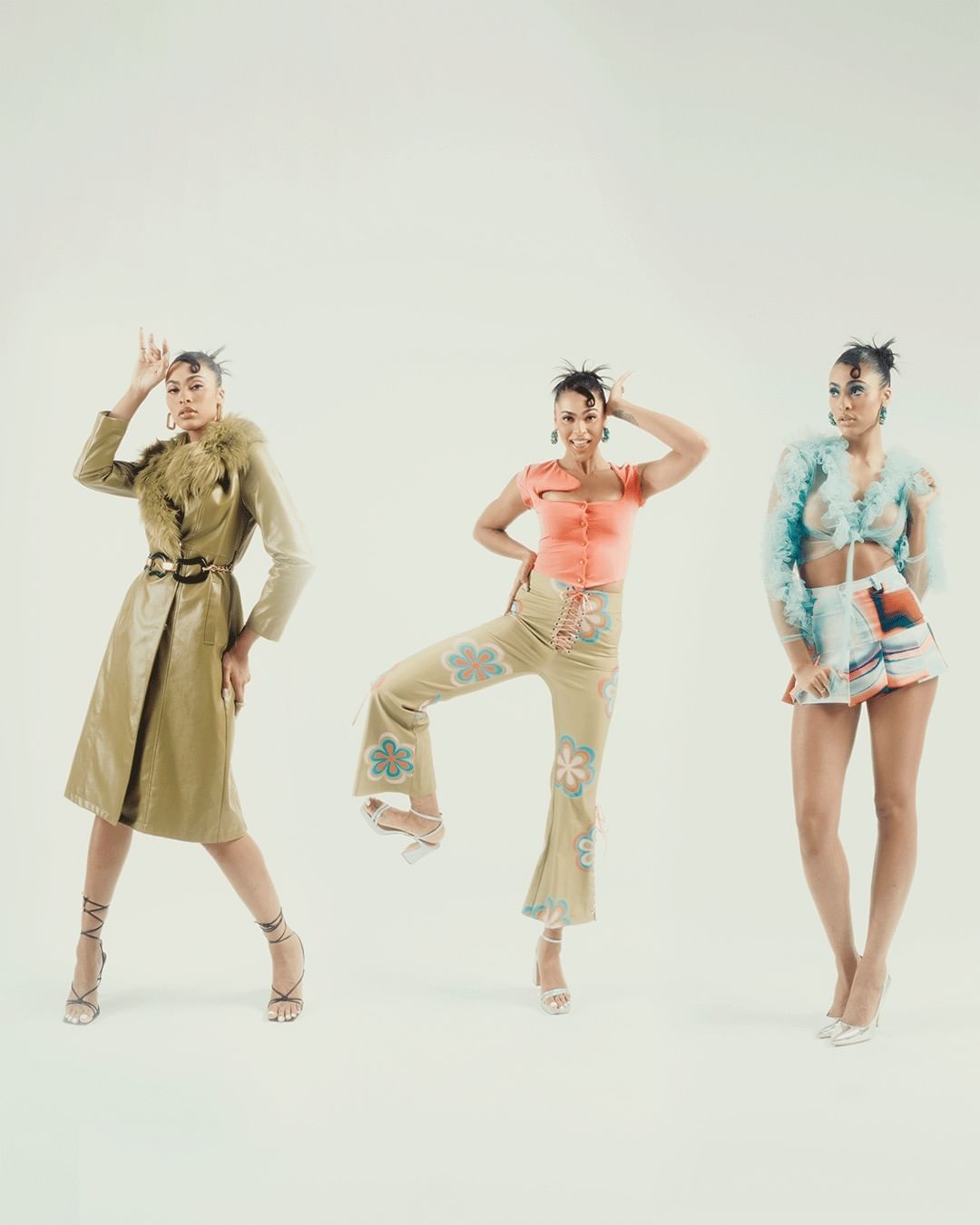 Three Black female fashion models showcase unique outfits in a bright studio. Poses include arms raised, standing, and confident expressions.