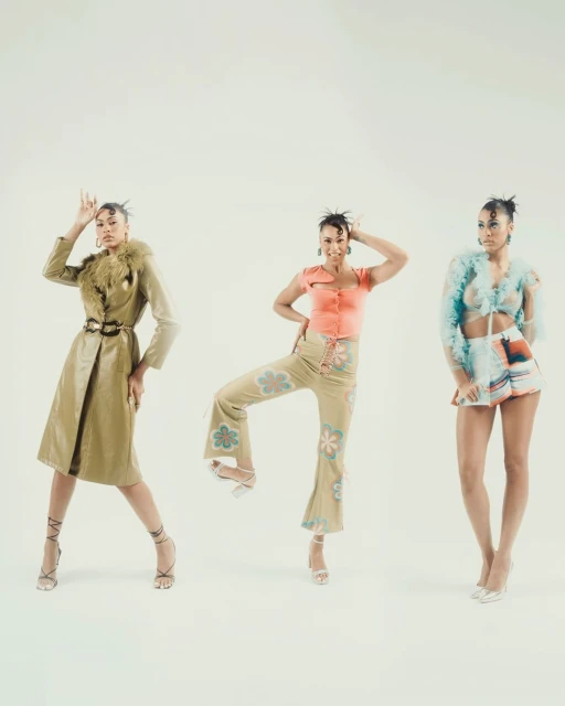 Three Black female fashion models showcase unique outfits in a bright studio. Poses include arms raised, standing, and confident expressions.