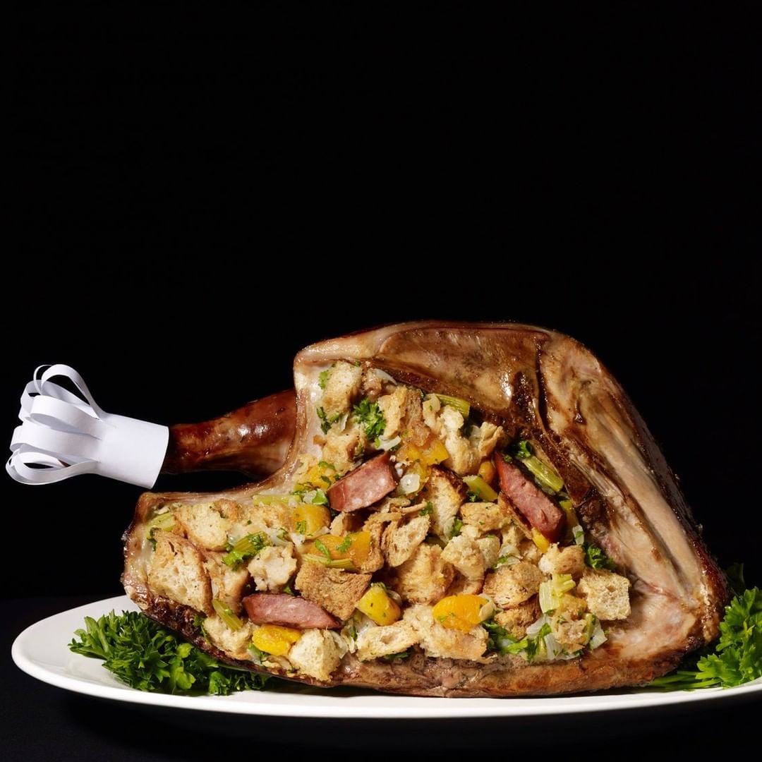 Festive food still life: stuffed roast turkey on a white plate with parsley garnish against a dark background. Food and Beverage.