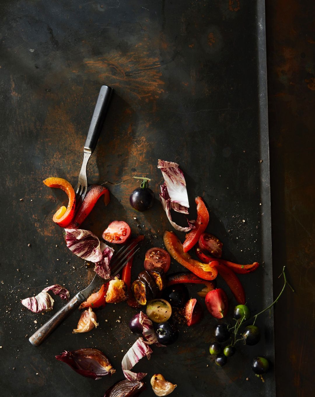 Overhead shot of red and purple vegetables on a dark, textured surface with a two-pronged fork, creating a vibrant and textured food composition.
