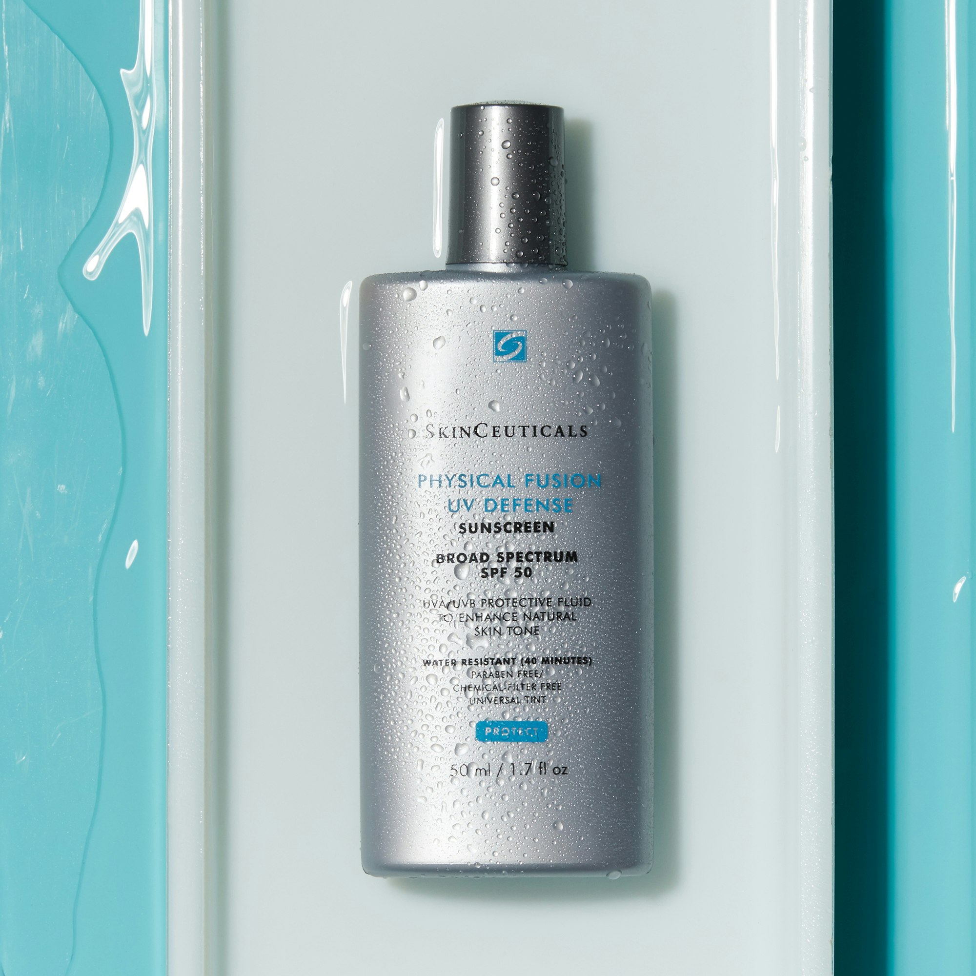 Silver bottle of SkinCeuticals Physical Fusion UV Defense sunscreen with water droplets against a light blue and white background.