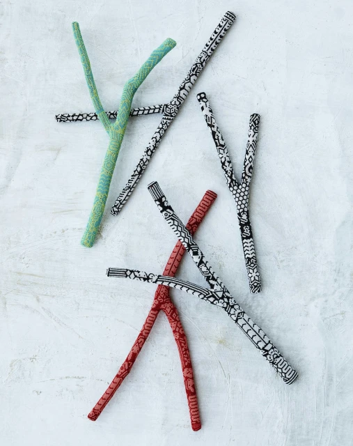 Overhead shot of several Y-shaped sticks with various black and white patterns and red and green colors scattered on a textured white surface.
