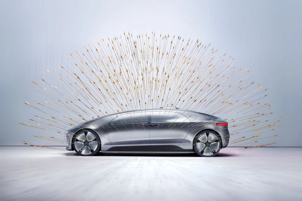 Sleek silver car sits in a photo studio with metallic rods arranged behind it, suggesting forward motion and innovative automotive design.