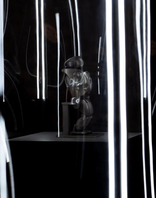 Abstract studio shot of a mannequin on a platform in front of a dark background with blurred streaks of white light. 
