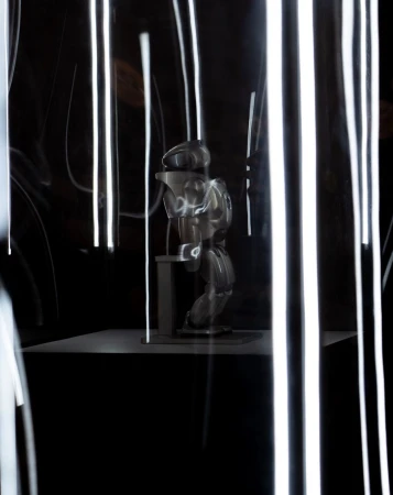 Abstract studio shot of a mannequin on a platform in front of a dark background with blurred streaks of white light. 