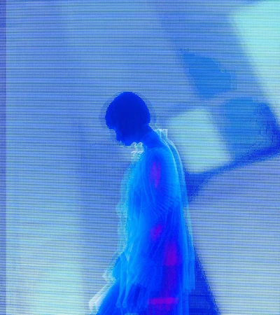 Silhouette of a person in profile against a vibrant blue digital screen backdrop with scan lines.