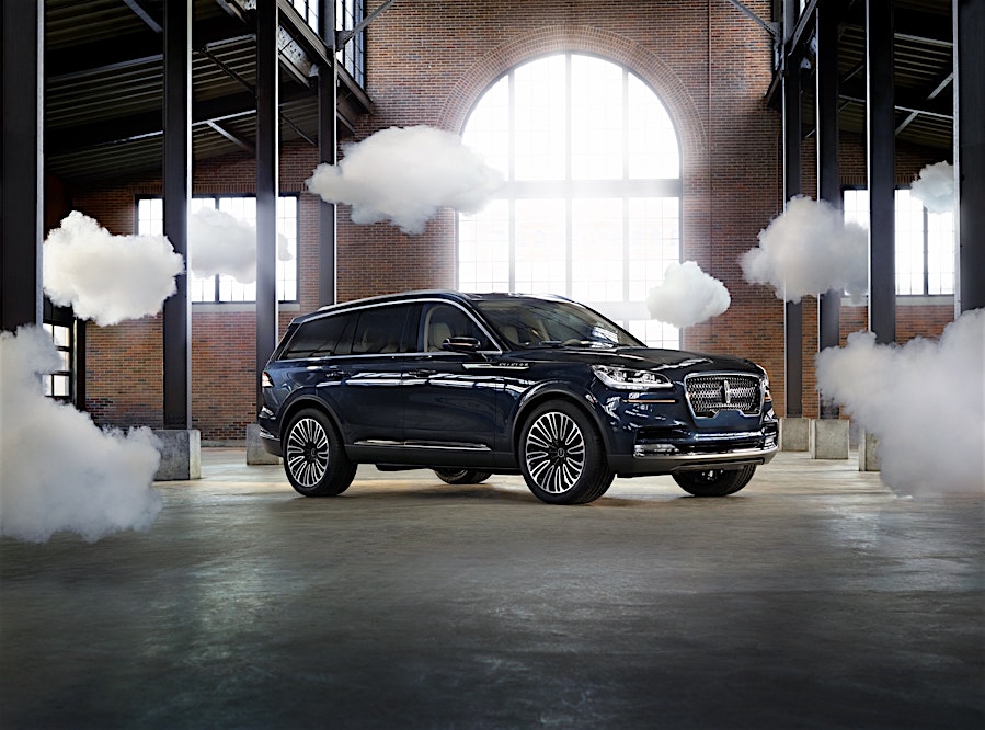 Aviation Blue Lincoln Aviator SUV displayed indoors with a decorative cloudscape, showcasing automotive design and luxury vehicle features.