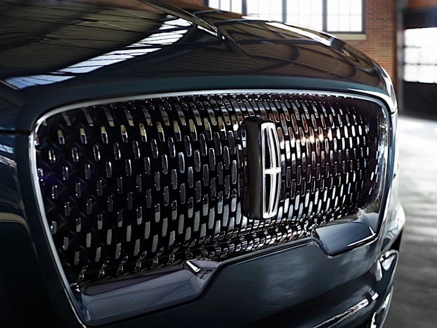 Close-up of a modern black Lincoln car grille with the Lincoln logo, showcasing the front design and automotive aesthetics indoors.