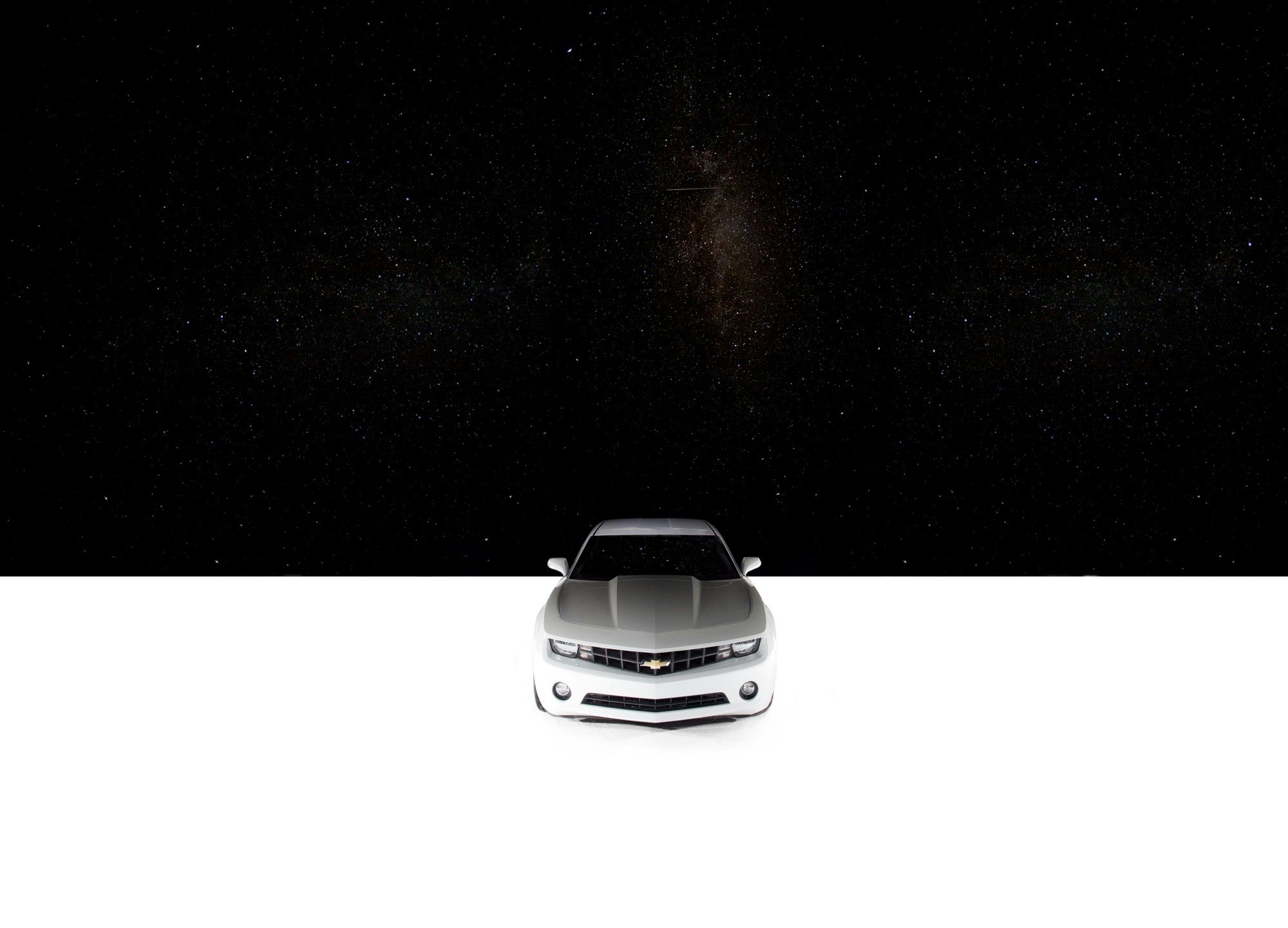 Front view of a silver Chevrolet Camaro parked against a contrasting black and white backdrop, emphasizing its modern design.