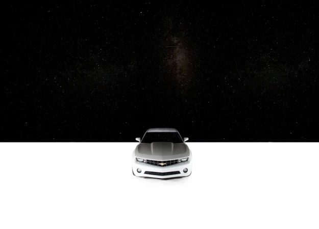 Front view of a silver Chevrolet Camaro parked against a contrasting black and white backdrop, emphasizing its modern design.