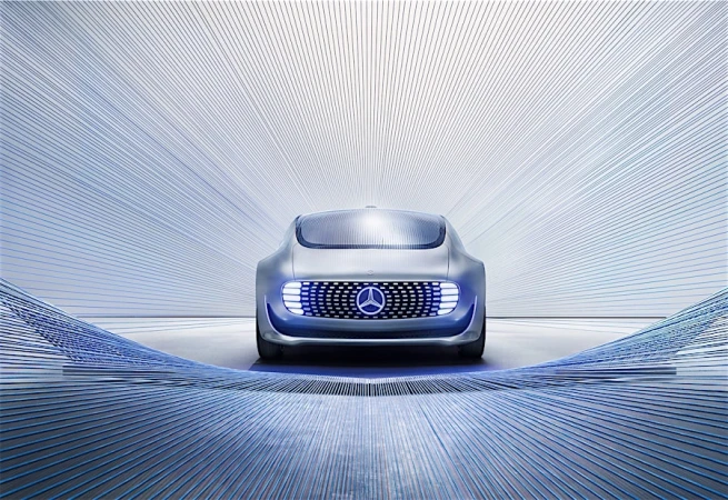 Silver Mercedes-Benz Vision AVTR concept car with blue illuminated grille, presented with blue light trails on a grey seamless background.
