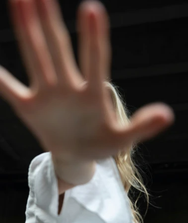Close-up of a person with blonde hair reaching out toward the camera with an outstretched hand, creating a strong blurred foreground effect.