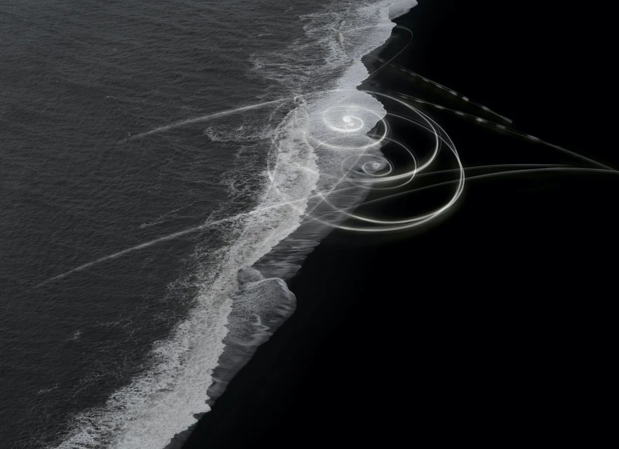 Abstract long exposure of ocean waves washing up on black sand beach with spirals of light painting adding surreal artistic touch.