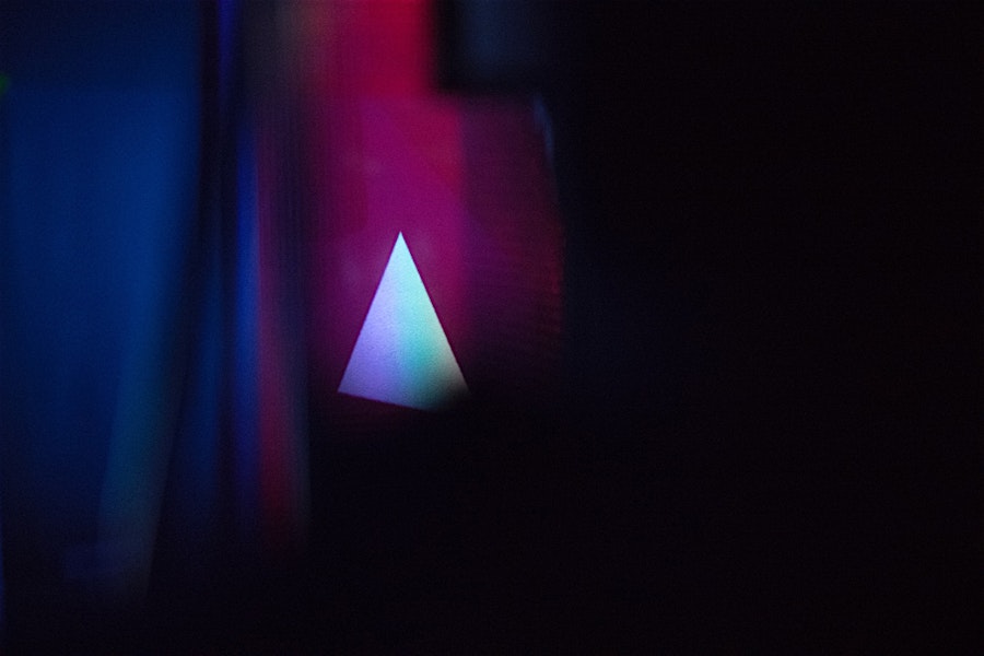 Abstract background featuring a glowing triangle against dark blue and purple tones, emphasizing modern digital aesthetics and lighting.