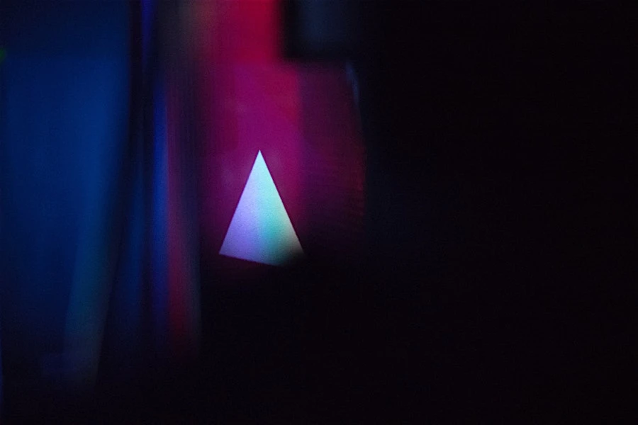 Abstract background featuring a glowing triangle against dark blue and purple tones, emphasizing modern digital aesthetics and lighting.