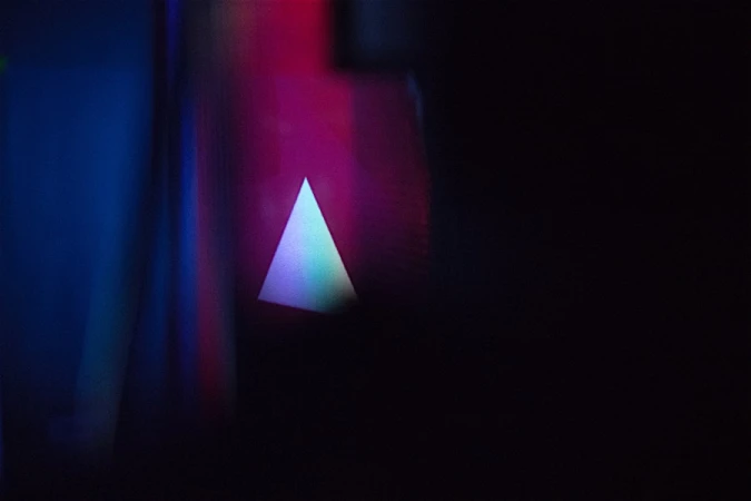 Abstract background featuring a glowing triangle against dark blue and purple tones, emphasizing modern digital aesthetics and lighting.