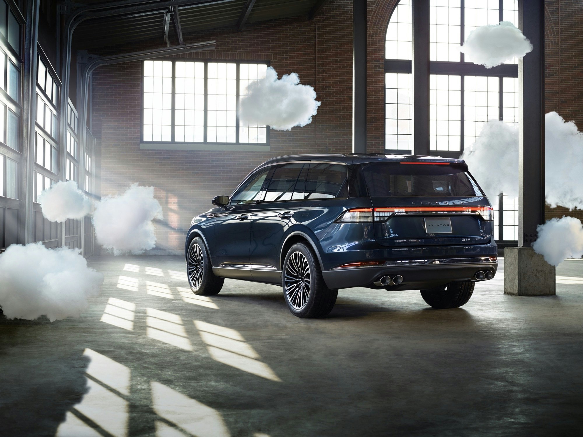 Dark blue Lincoln Corsair SUV shown in an airy industrial space with large windows and artificial clouds as creative visual element.