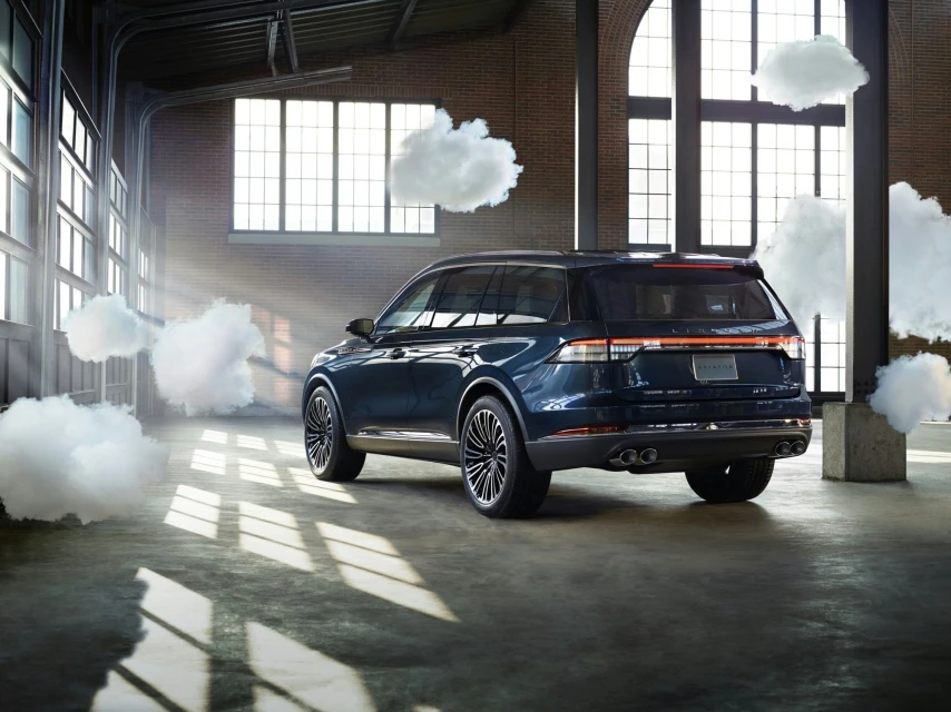 Dark blue Lincoln Corsair SUV shown in an airy industrial space with large windows and artificial clouds as creative visual element.