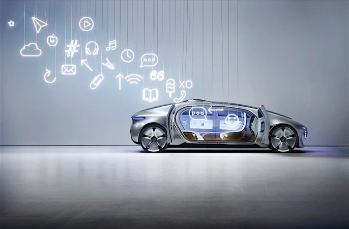 Futuristic silver concept car displayed indoors with illuminated social media icons suspended from the ceiling in a well-lit studio.