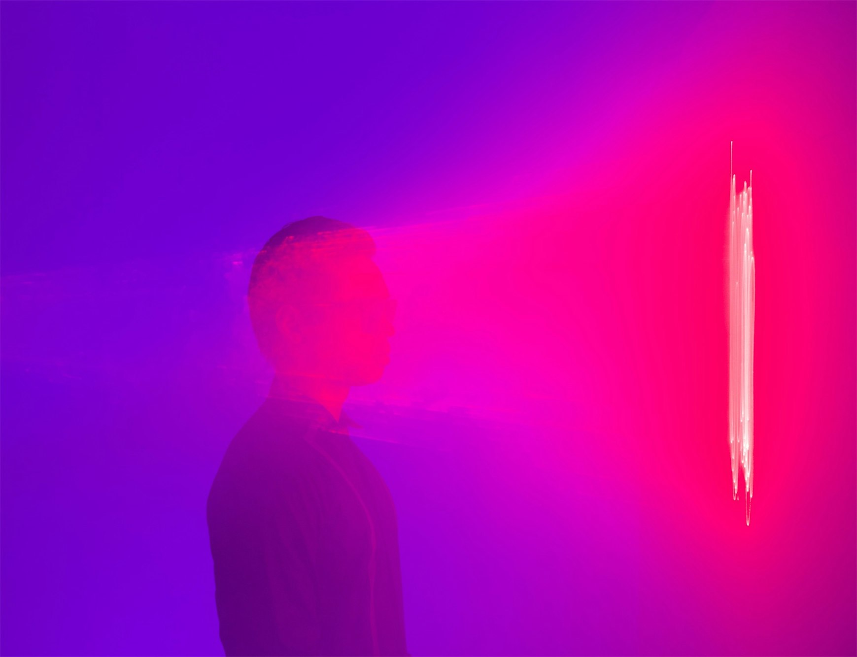 Silhouette of a person against a vibrant gradient of blue and pink, featuring a vertical light streak, creating a dynamic and modern visual.