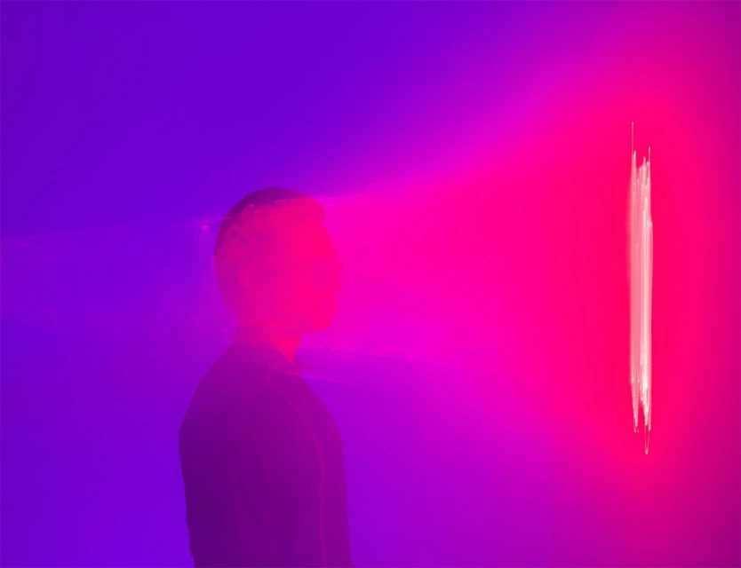 Silhouette of a person against a vibrant gradient of blue and pink, featuring a vertical light streak, creating a dynamic and modern visual.