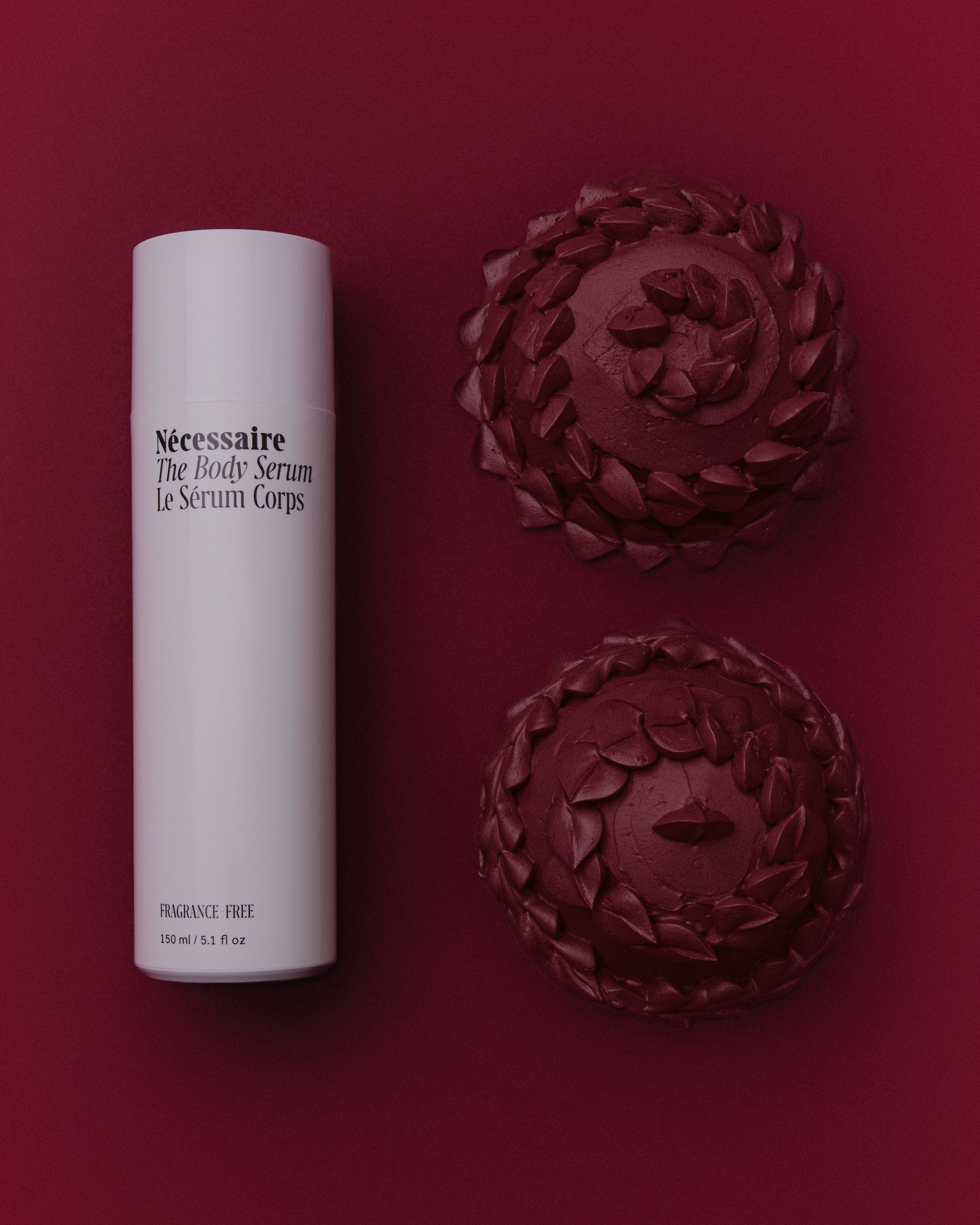 Minimalist product shot of Nécessaire body serum in white bottle with decorative spheres on a dark red backdrop. Beauty concept.
