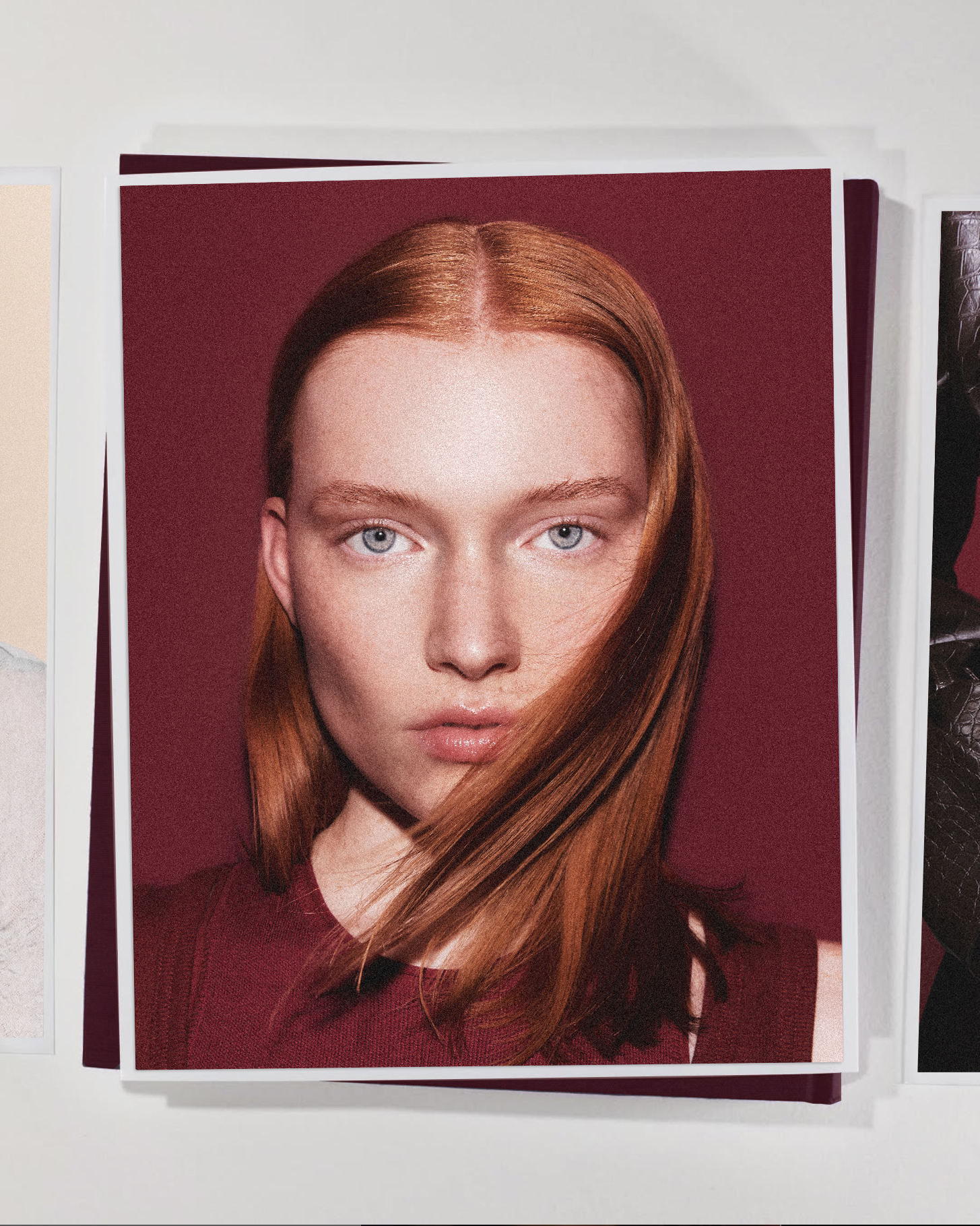 Close-up of a woman with red hair and blue eyes, wearing a maroon shirt, in front of a maroon background; framed by other portrait images.