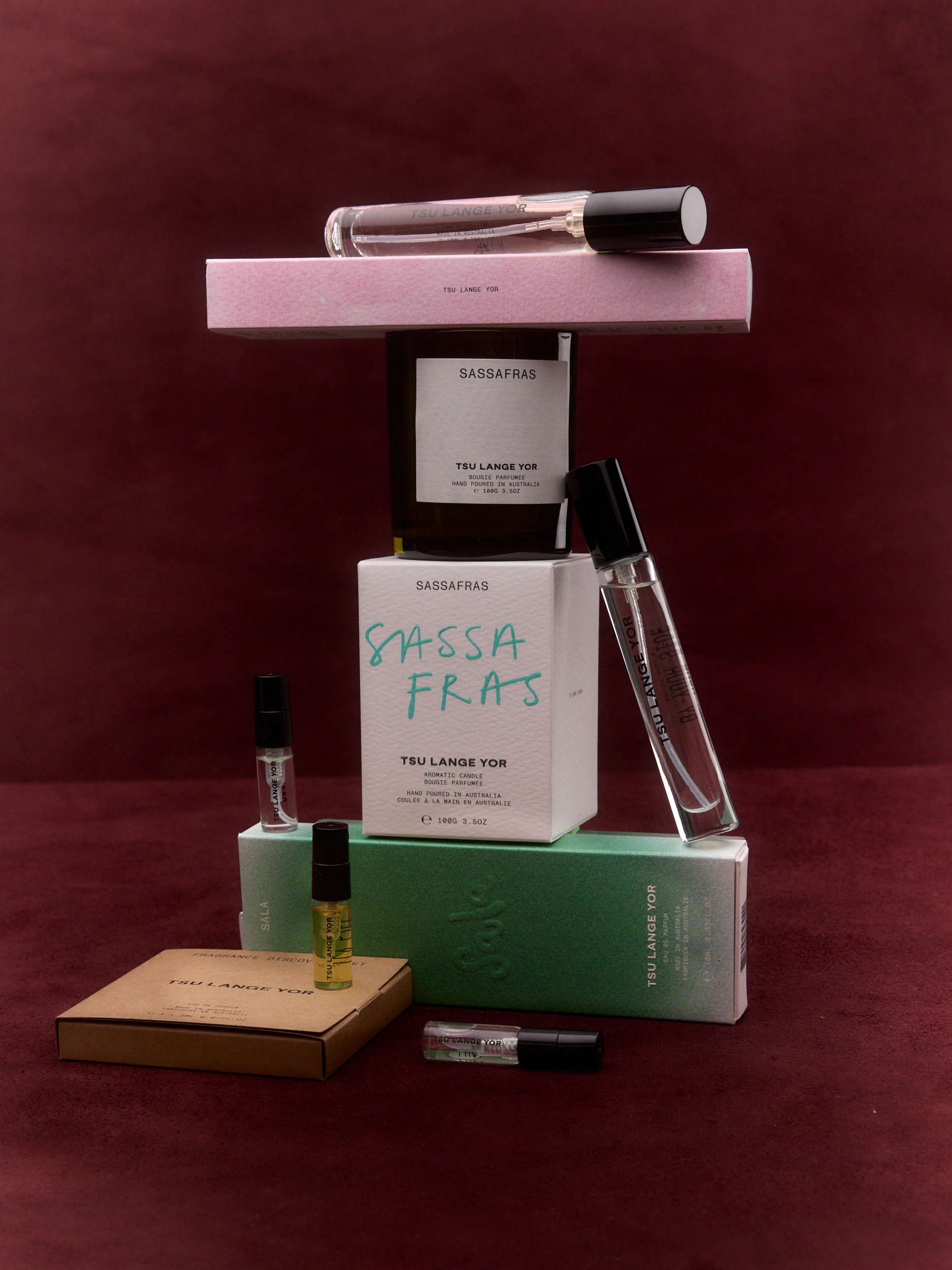 Arrangement of Sassafras Tsu Lange Yor perfume bottles and product boxes in shades of white, green, brown, and pink.