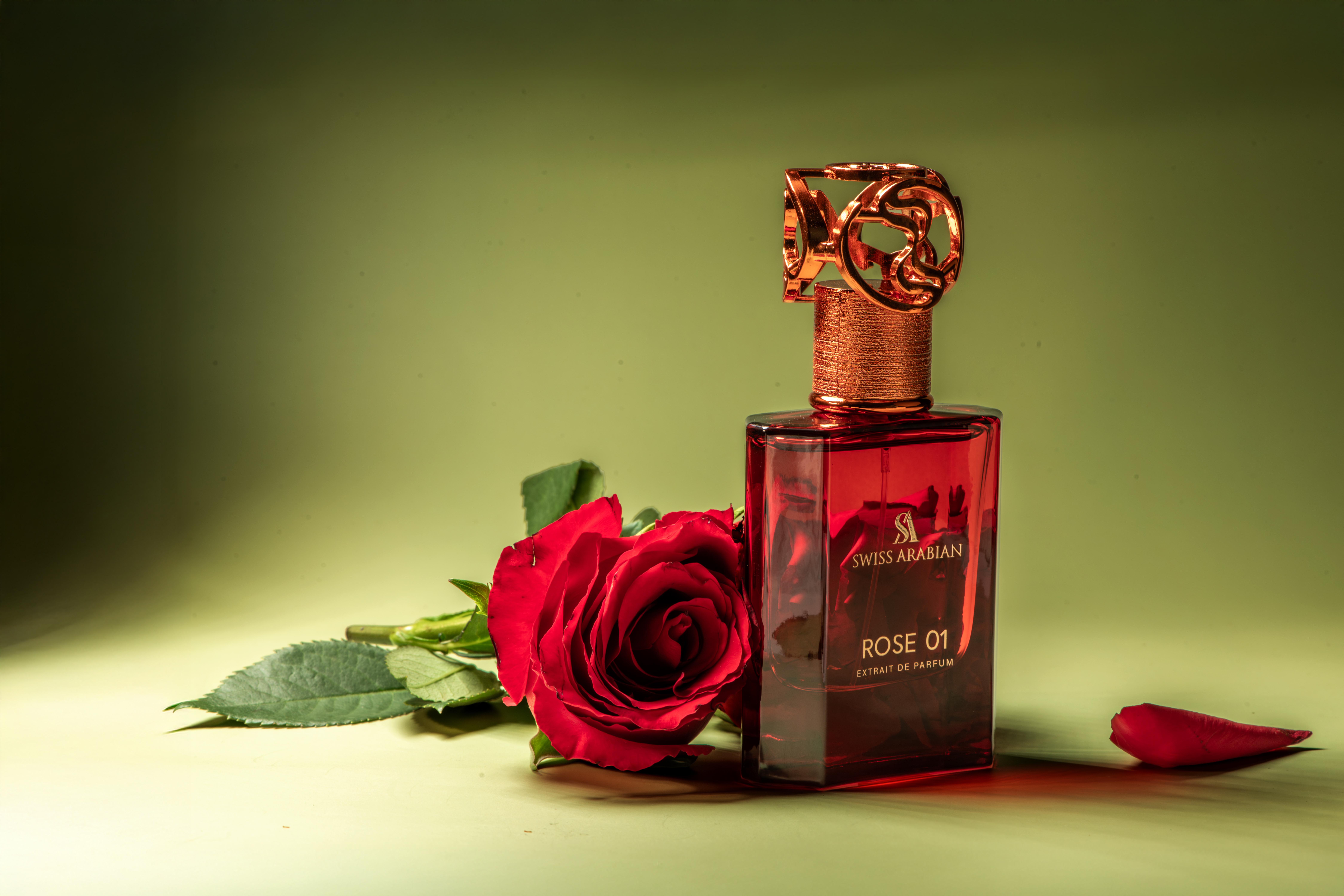 Perfume bottle by Swiss Arabian, Rose 01, with red rose on green background. Square bottle with decorative gold top and label.