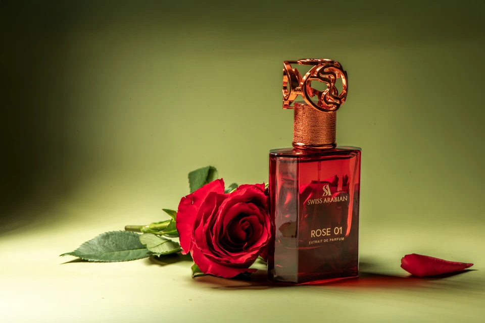 Perfume bottle by Swiss Arabian, Rose 01, with red rose on green background. Square bottle with decorative gold top and label.