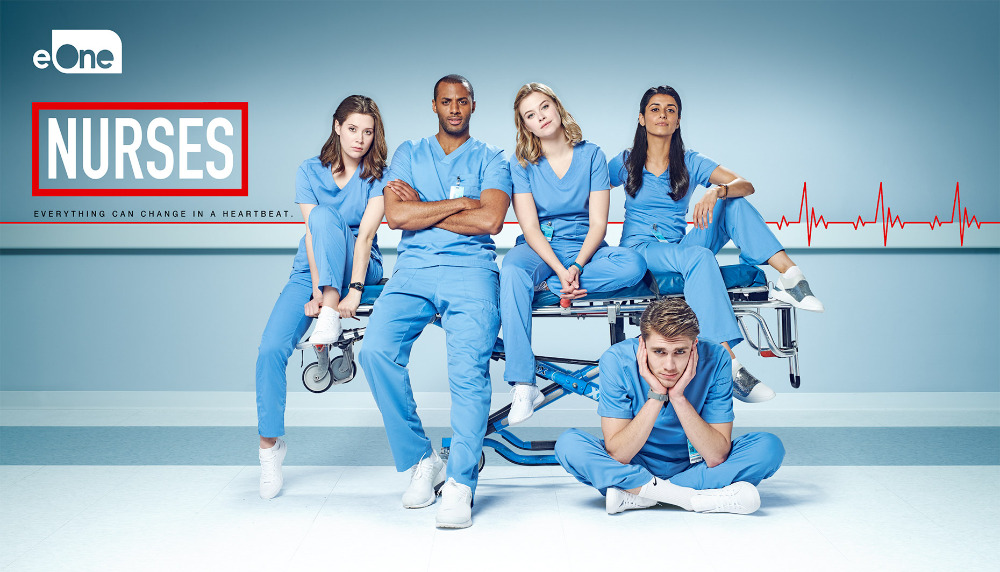 Group shot of five young adult nurses in blue scrubs sitting on a hospital gurney in a photo studio against a blue background.