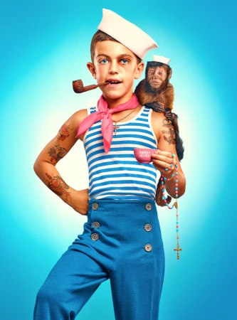 Young boy in a sailor outfit with tattoos and a pipe, accompanied by a monkey, posing against a light blue gradient background.