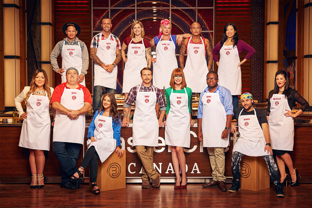 Group photo of MasterChef Canada contestants in aprons, posing in a studio with the show's logo, showcasing culinary competition.