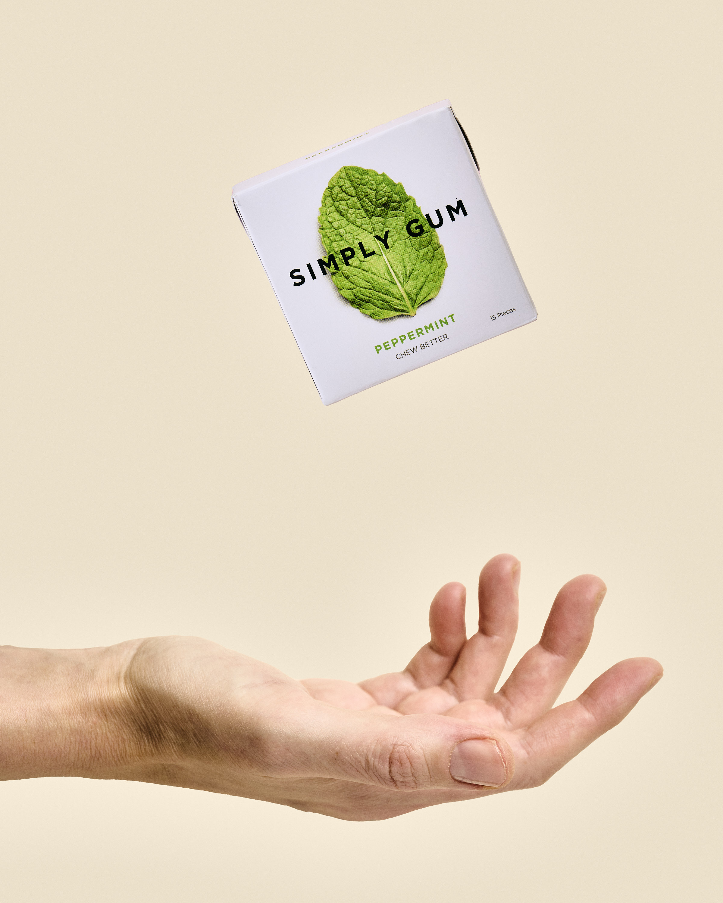 Package of peppermint chewing gum floating above a hand against a neutral background, product shot for food and beverage industry.