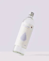 Clear glass bottle of Still Mineral Water tilted at an angle against a minimal pale pastel studio background.