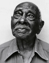 Close-up portrait of an elderly Black man looking upward with a thoughtful expression, photographed by Paul Mobley.
