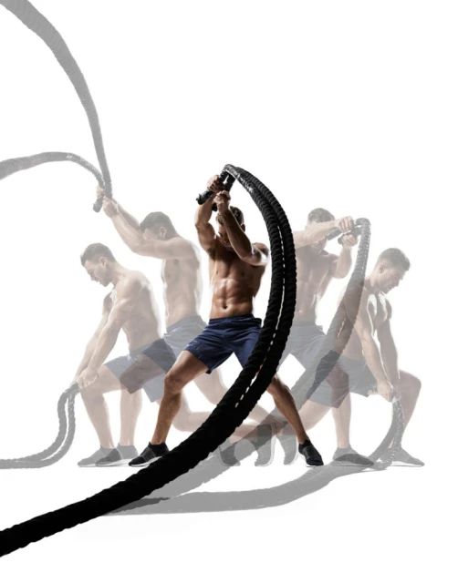 Muscular man in blue shorts exercising with battle ropes in a dynamic multiple exposure shot against a bright white background.