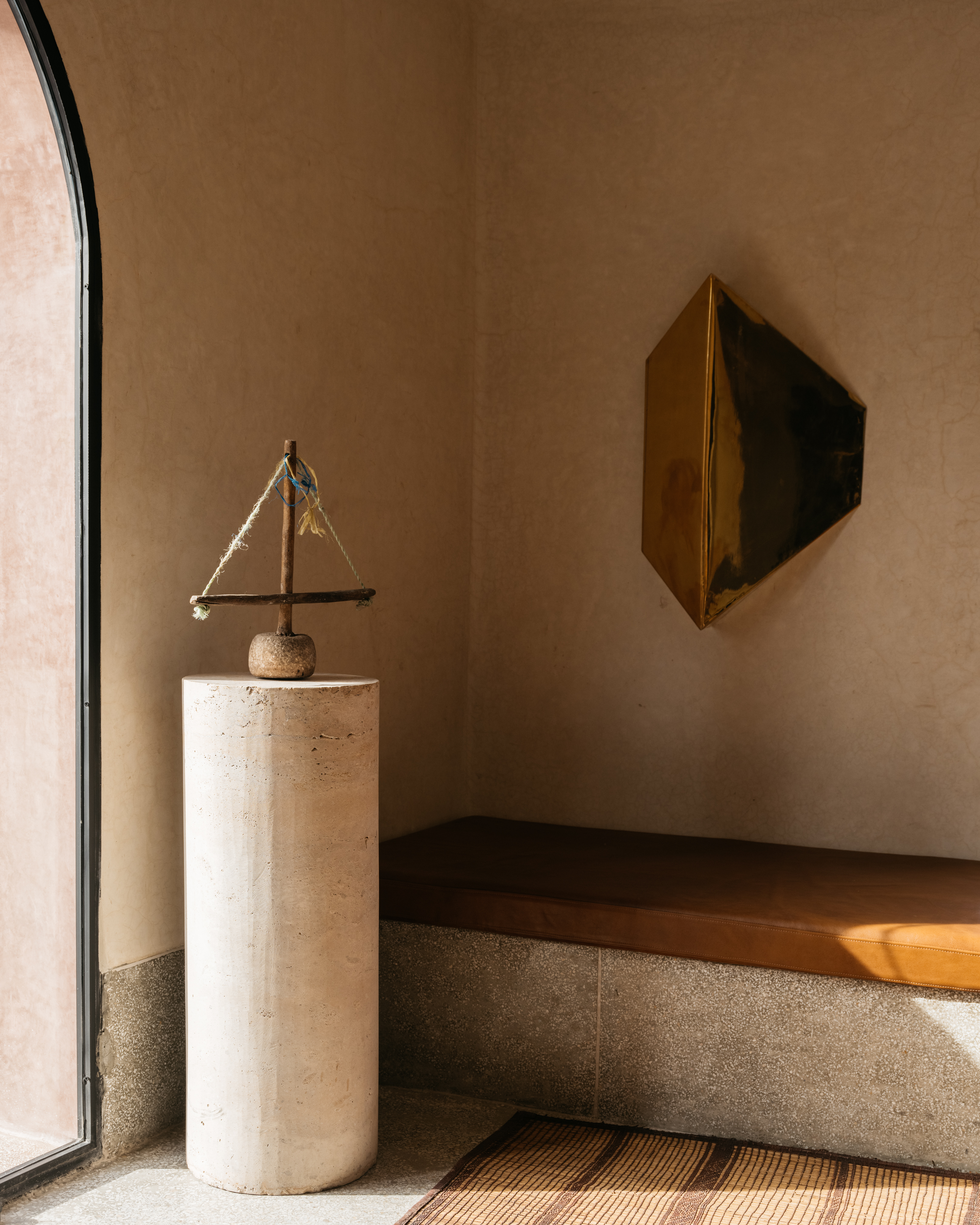 Interior view with decorative sailboat sculpture atop a cylindrical plinth, set against a backdrop of textured walls and modern art.