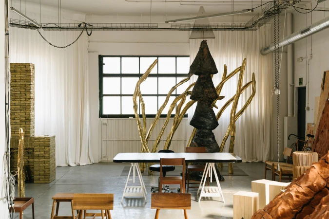 Industrial-style room featuring a sculpture, table, chairs, and natural light through a window, creating an artistic and functional space.