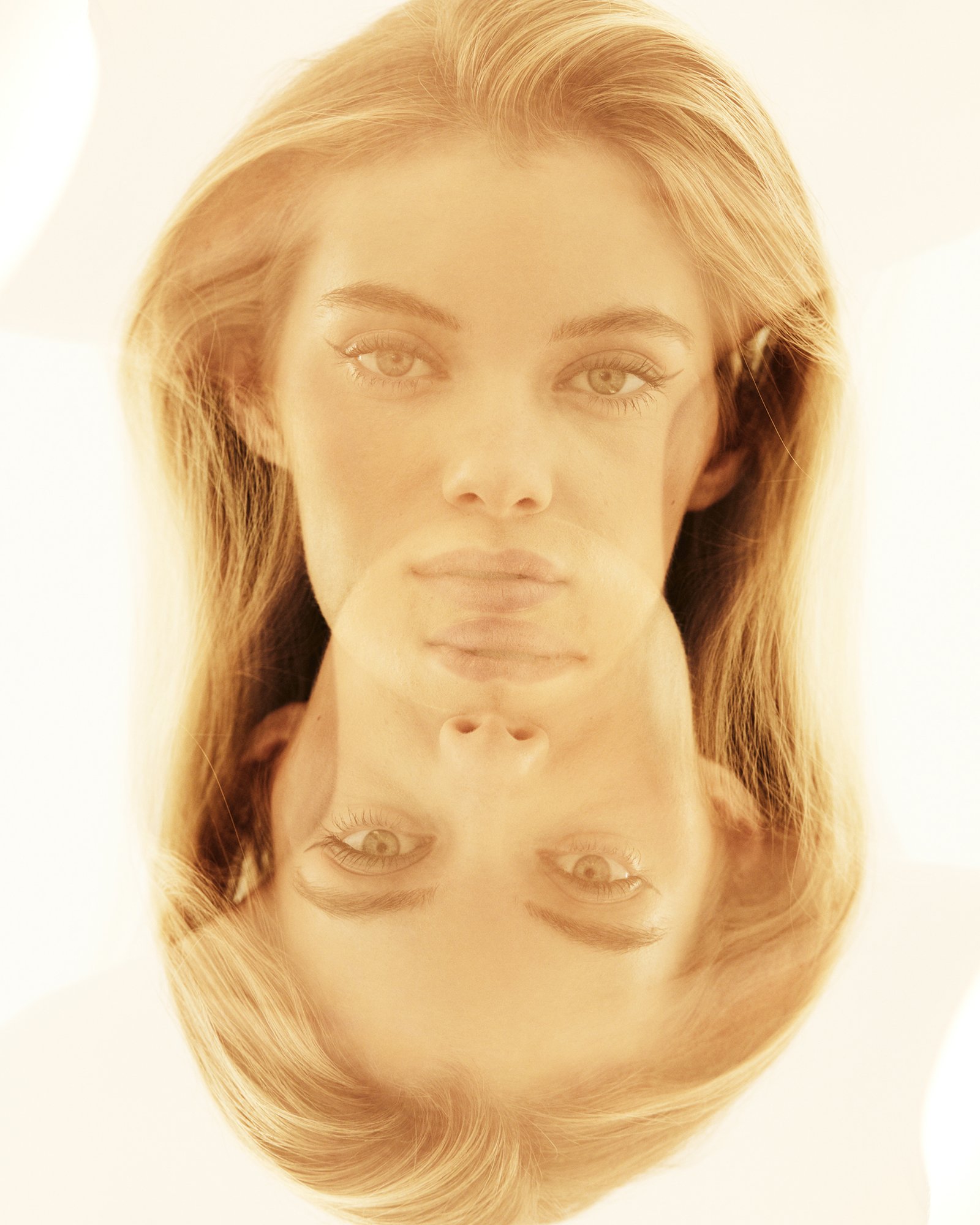 Portrait of a fair-skinned woman with blonde hair, duplicated and inverted with a blurred effect, creating an ethereal, mirrored composition.