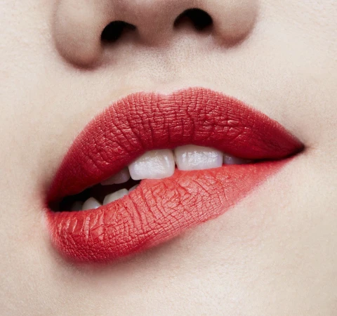 Close-up of a woman's face featuring red lipstick, highlighting the makeup and beauty aspects with a focus on the lips and teeth.