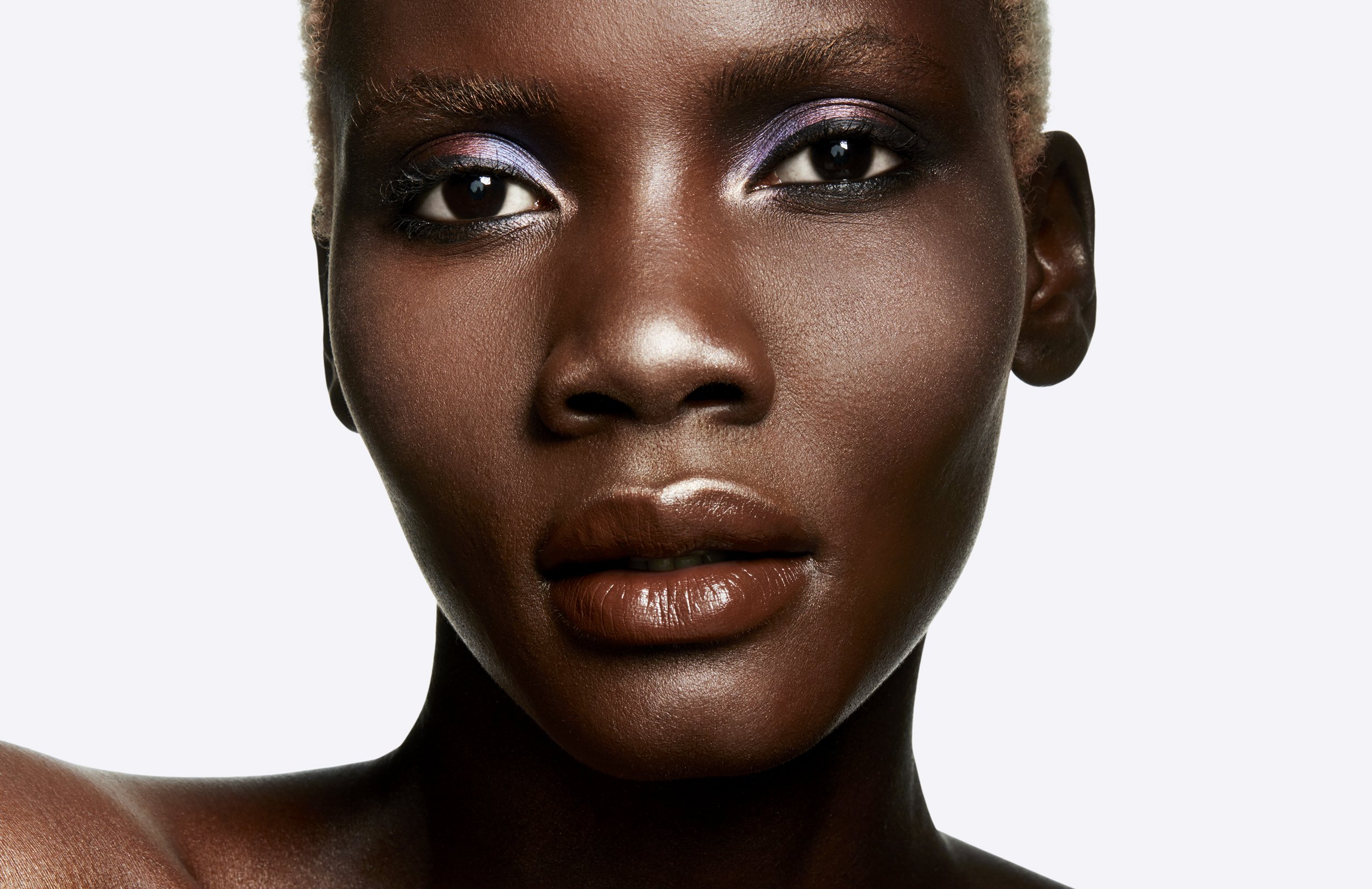 Close-up portrait of a woman with short hair and neutral makeup against a bright white background in a photo studio setting.