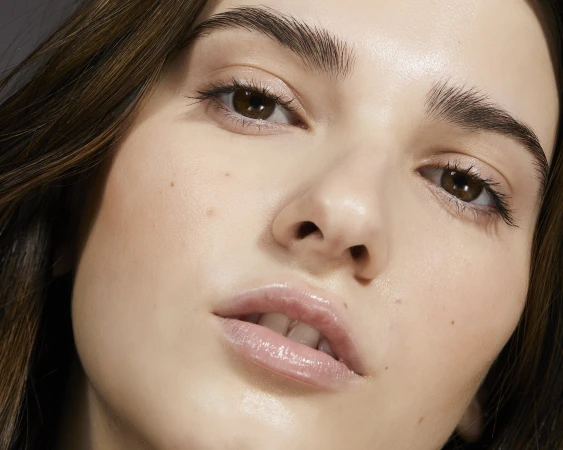 Close-up portrait of a woman with glossy lips and defined eyebrows directed by Bri Johnson in New York.