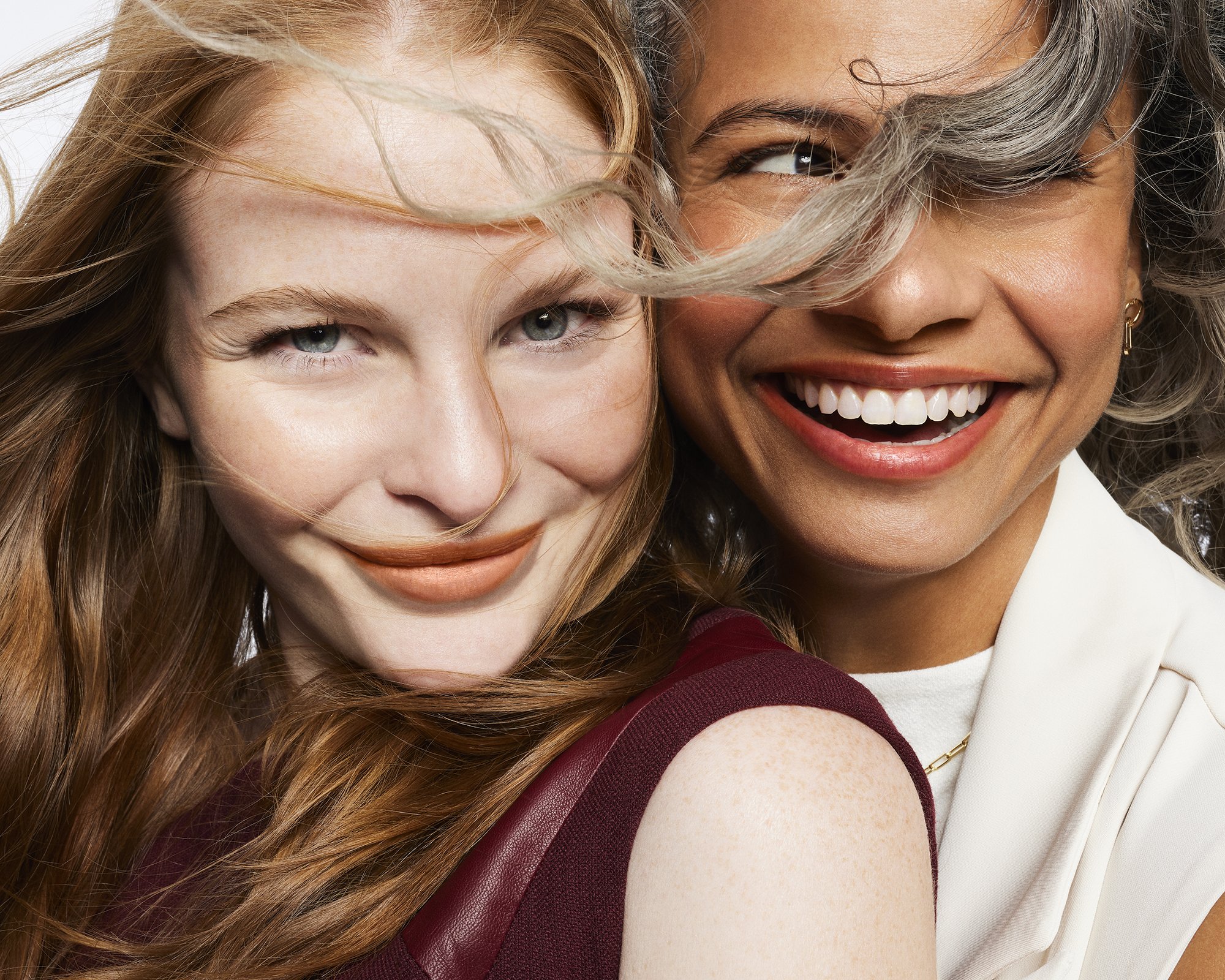 Close-up portrait of two smiling women with flowing hair and natural makeup directed by Bri Johnson in New York.
