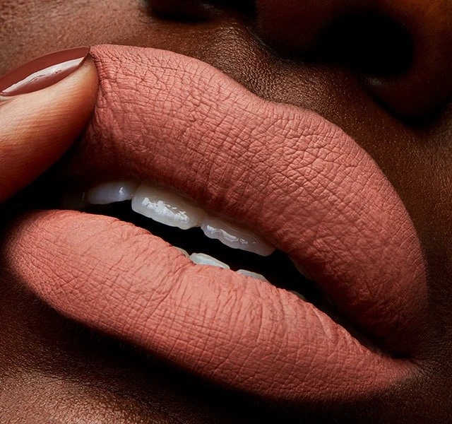 Close-up of a person's face with a medium skin tone, wearing a matte lipstick, showcasing the texture and color of the makeup.