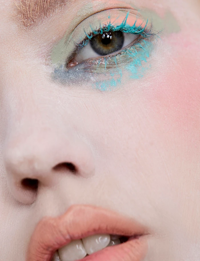Close-up portrait of a woman with vibrant turquoise mascara and pastel eyeshadow by director Bri Johnson