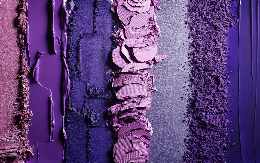 Close-up of colorful purple and pink textured eyeshadow swatches for beauty and cosmetics, creating a vibrant makeup pattern.