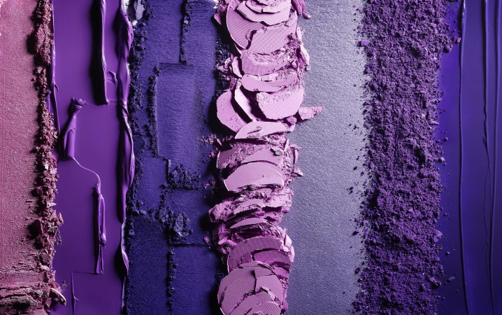 Close-up of colorful purple and pink textured eyeshadow swatches for beauty and cosmetics, creating a vibrant makeup pattern.